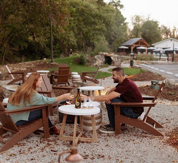 A couple having wine and s'mores by a firepit.