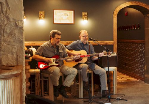 Two men playing guitars in a hotel lobby.