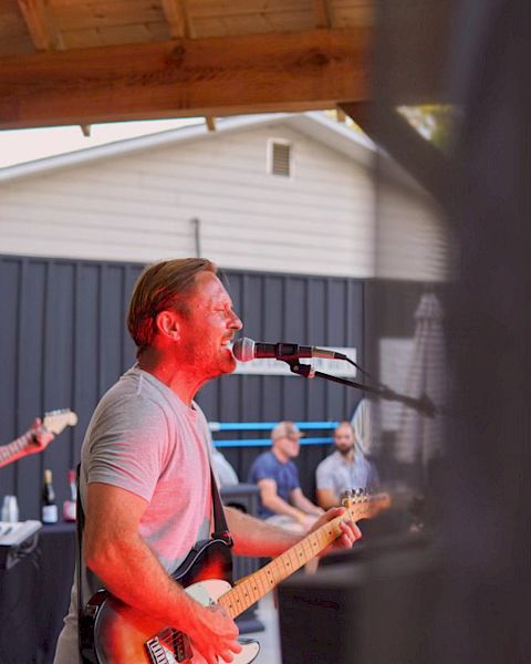 A man signing into a microphone and playing the guitar.