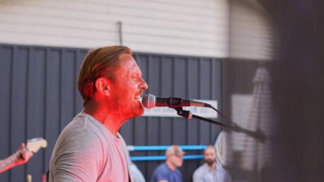 A man signing into a microphone and playing the guitar.