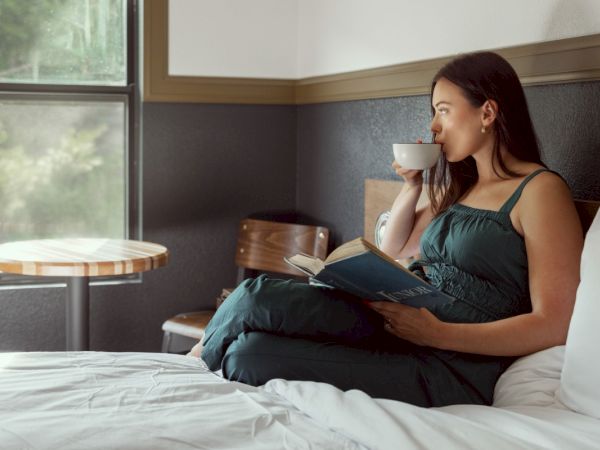 A woman having coffee and reading in bed.