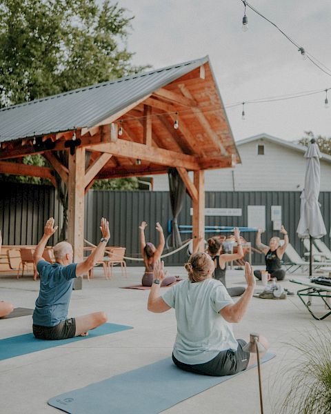 A group of people practicing yoga poolside at The Ozarker.