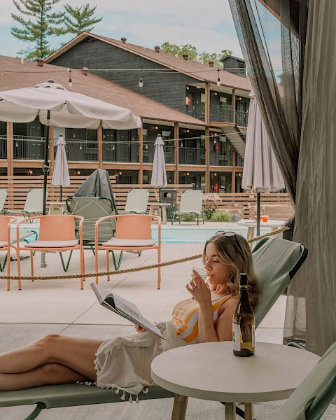 A woman sipping wine in a cabana by the pool.