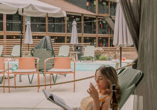 A woman sipping wine in a cabana by the pool.
