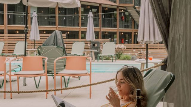 A woman sipping wine in a cabana by the pool.